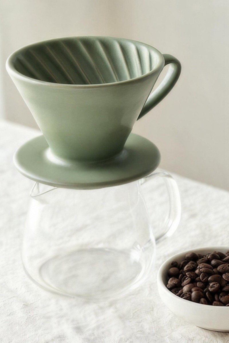 Zielony ceramiczny dripper stoi na szklanym dzbanku.
